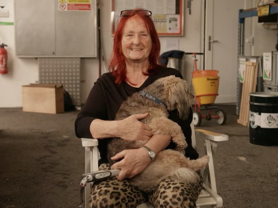 Eine Frau mit roten Haaren hat einen Hund auf ihrem Schoss.