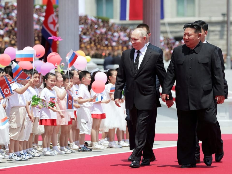 Putin läuft mit Kim neben Kindern vorbei. 