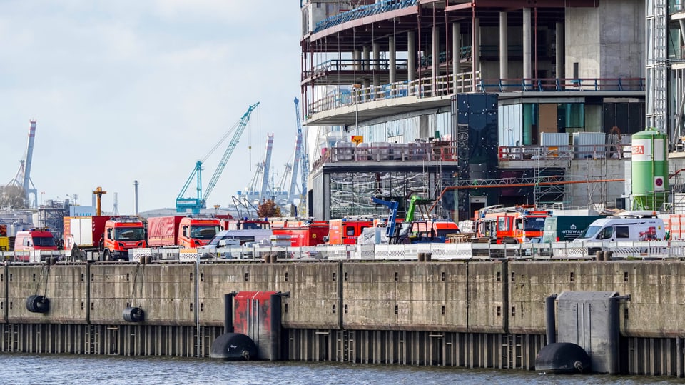 Zahlreiche Feuerwehrautos reihen sich vor der Baustelle aneinander. 