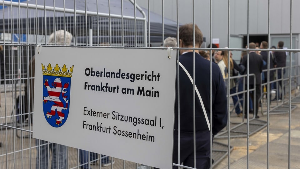 Personen stehen in der Schlange am Oberlandesgericht Frankfurt am Main.