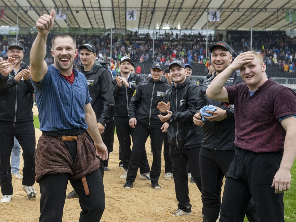 Männer jubeln in einem Stadion nach einem Sportevent.