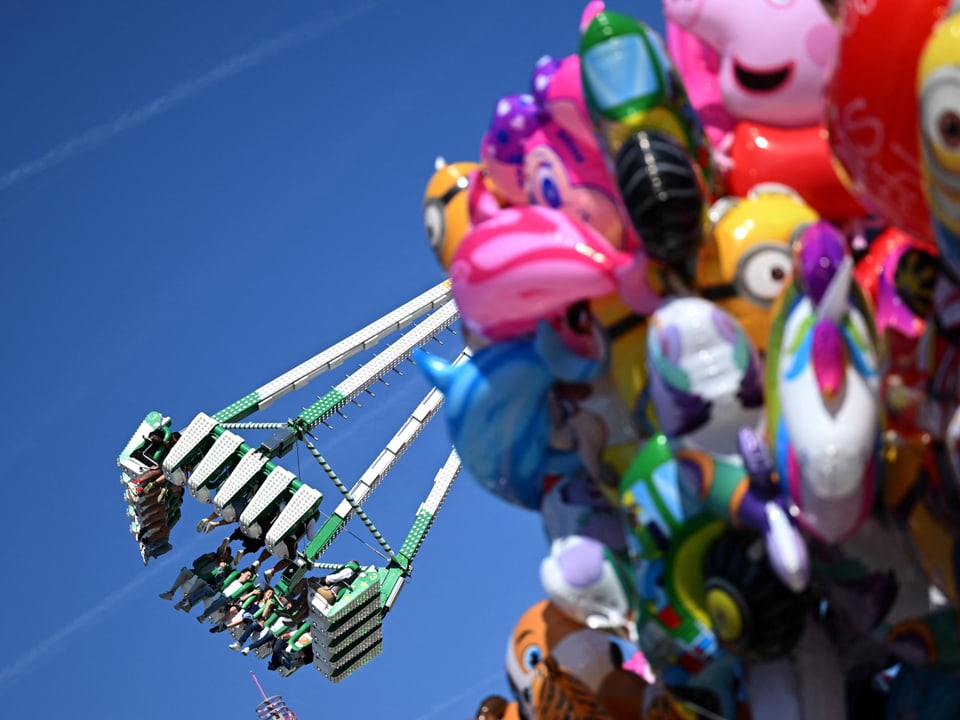 Fahrgeschäft auf Jahrmarkt mit Ballons im Vordergrund.