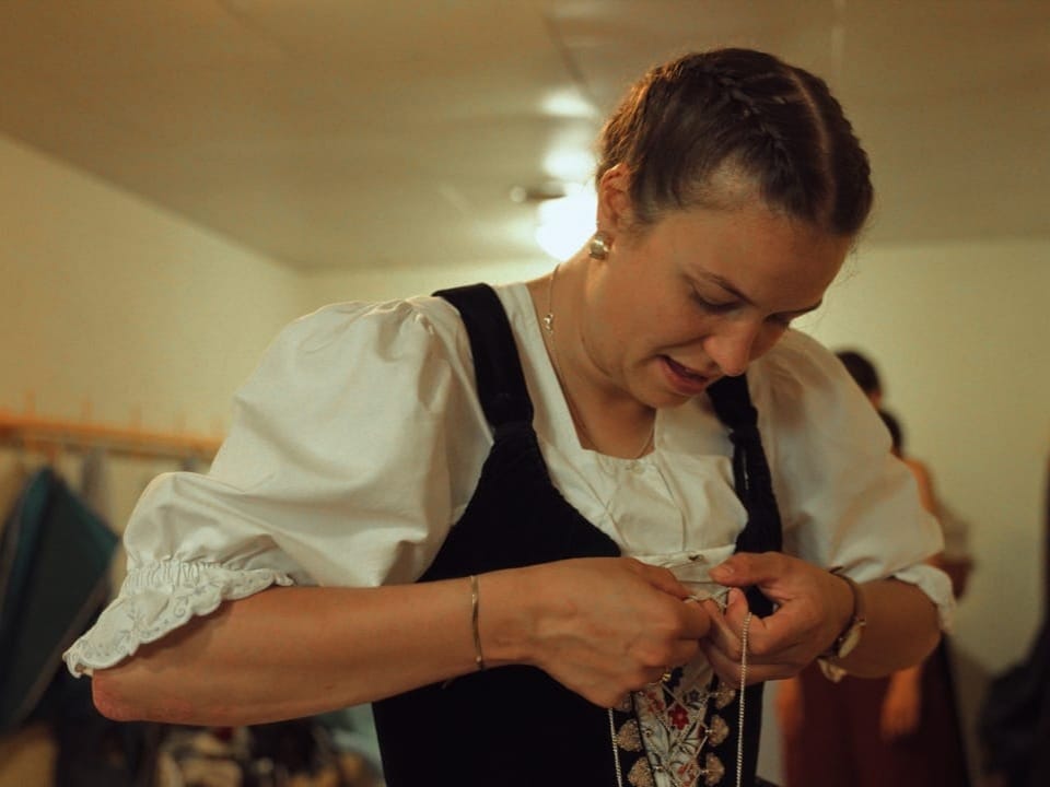 Frau in traditioneller Kleidung beim Schnüren einer Weste.