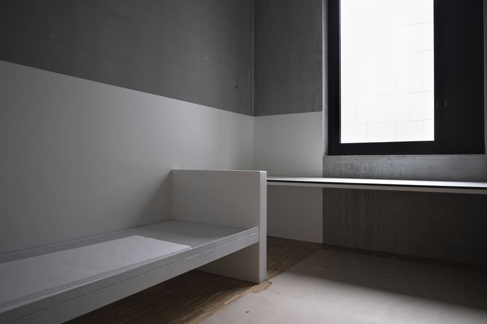 Gefängniszelle mit einem Bett und Fenster.