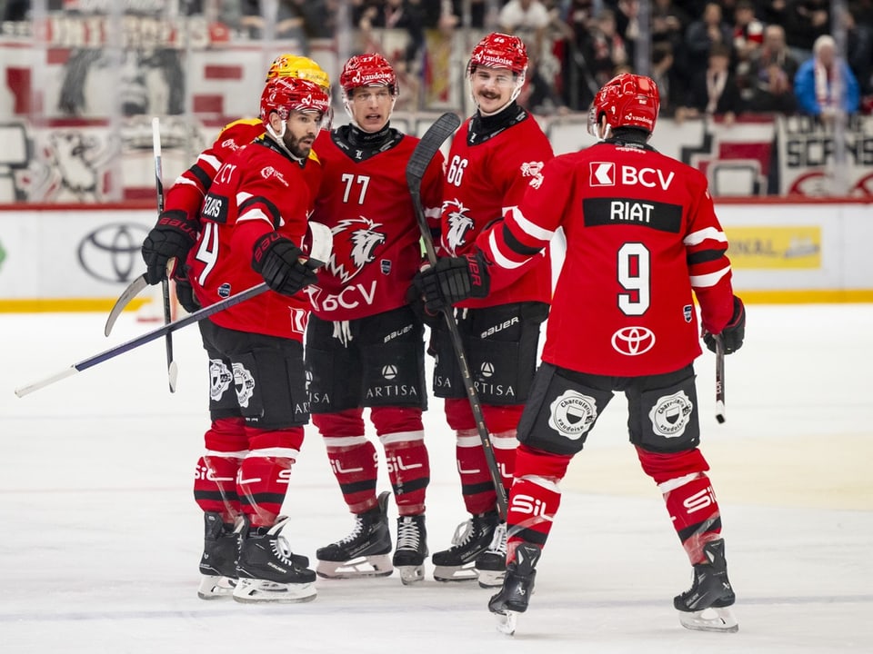 Eishockeyspieler in roten Trikots feiern auf dem Eis.