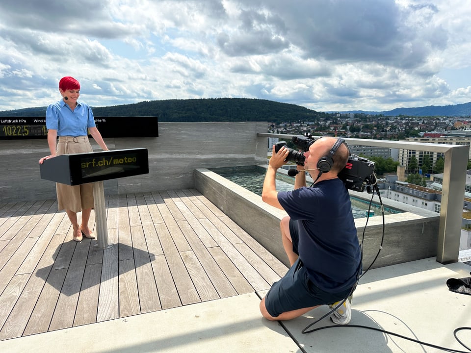 Fernsehmoderatorin moderiert das Wetter, ein Kameramann filmt sie dabei.