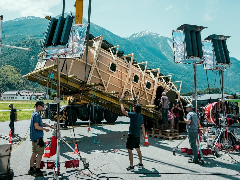 Filmcrew dreht vor künstlichem Haus in Berglandschaft.