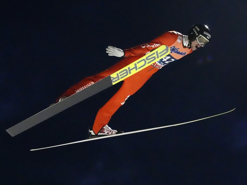 Skispringer im Flug bei Nacht.