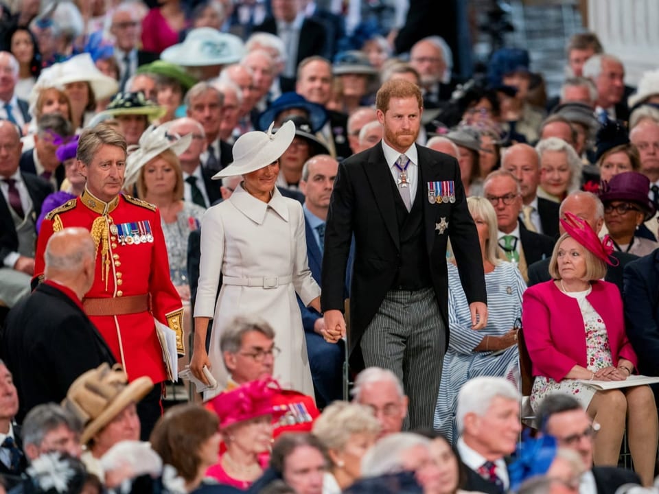 Harry und Meghan schreiten Hand in Hand am Thronjubiläum der Queen.