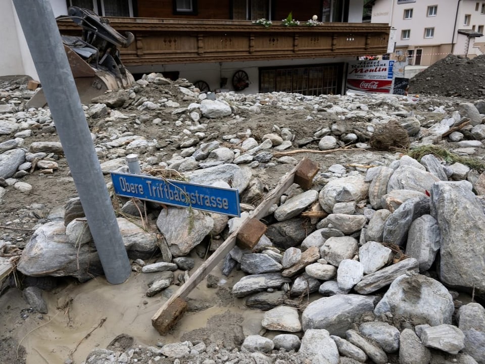 Strassenschild im Schutt nach Erdrutsch.