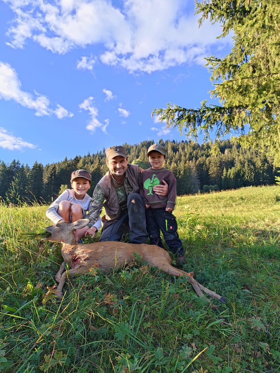 Ein Jäger und zwei Kinder mit einer Rehgeiss, in einer herbstlichen Landschaft.