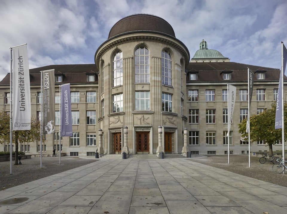 Universitätsgebäude mit Flaggen der Universität Zürich.