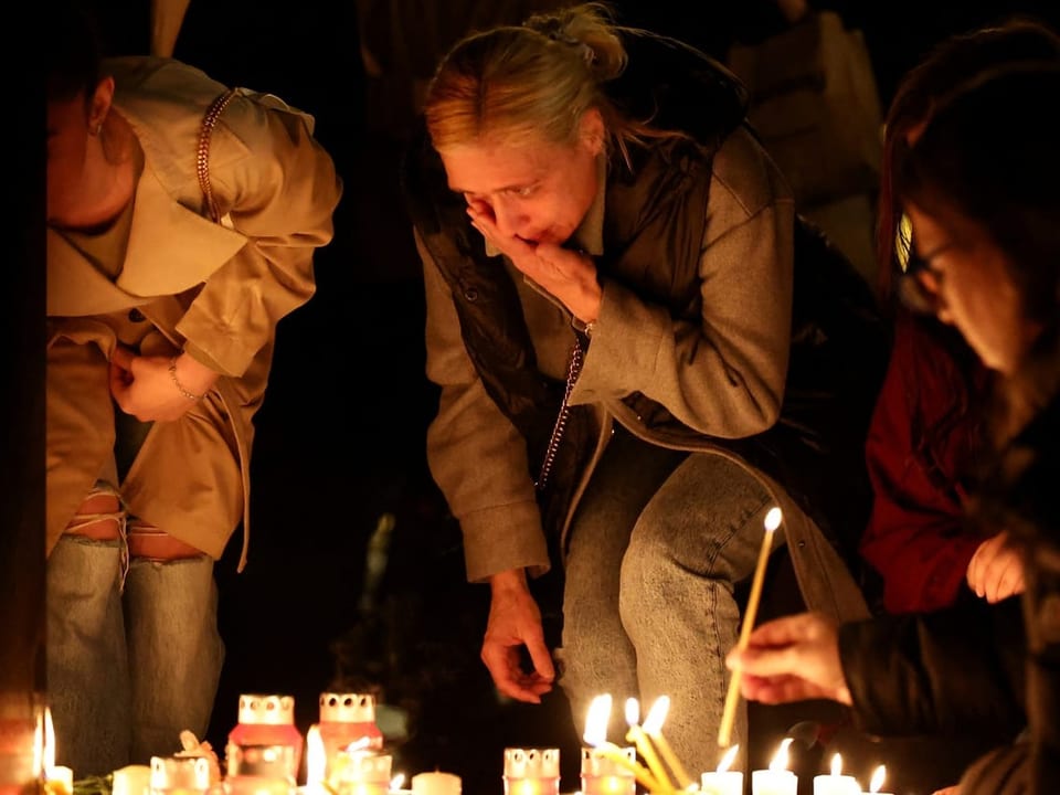 Menschen zünden Kerzen bei einem Gedenkaltar an.