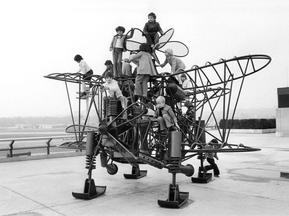 Kinder klettern auf einem skulpturalen Klettergerüst in Flugzeugform.
