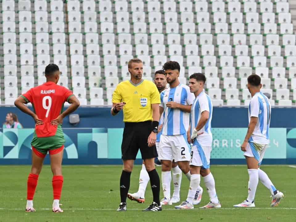 El árbitro de fútbol habla con los jugadores en el campo.