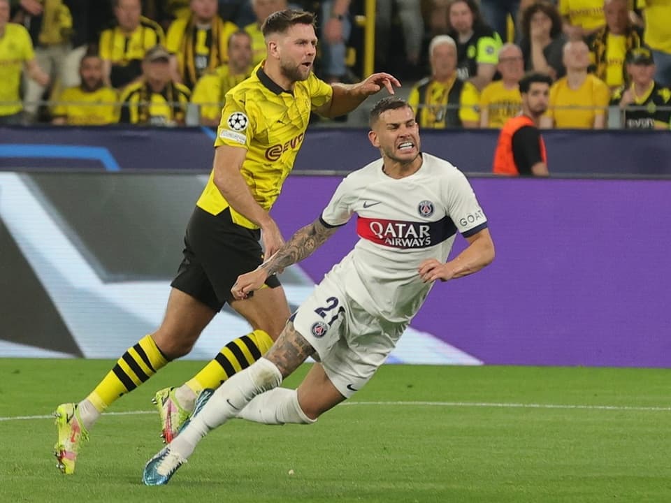 Zwei Fussballspieler im Duell um den Ball während eines Spiels, einer in gelb-schwarz, der andere in weiss.