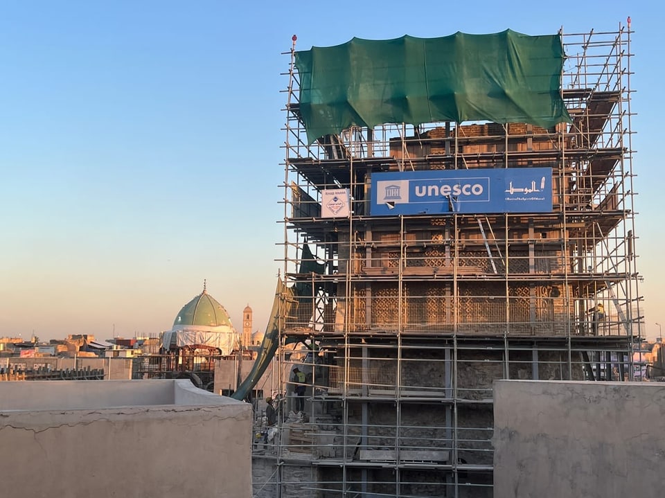 Baugerüst mit UNESCO-Banner an historischem Gebäude.