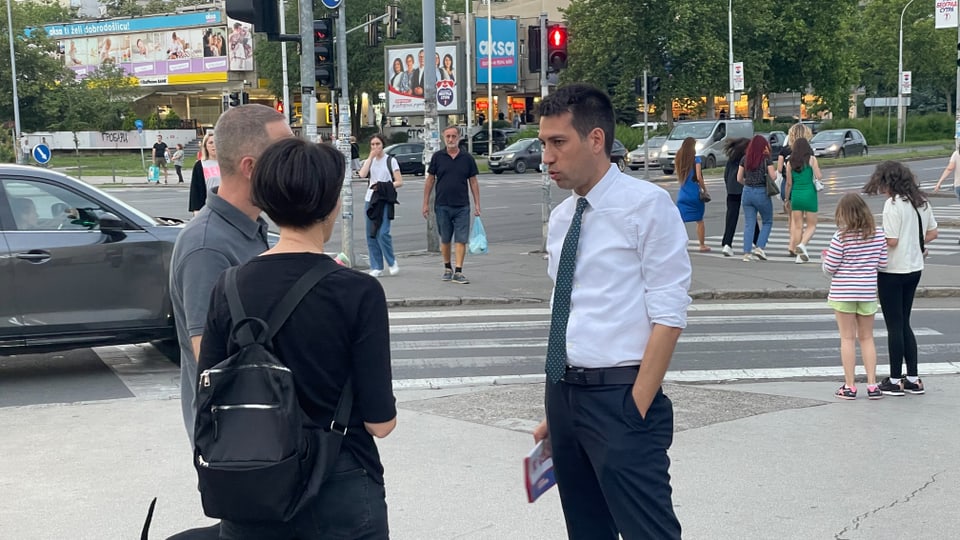 Menschen unterhalten sich an einer belebten Kreuzung.