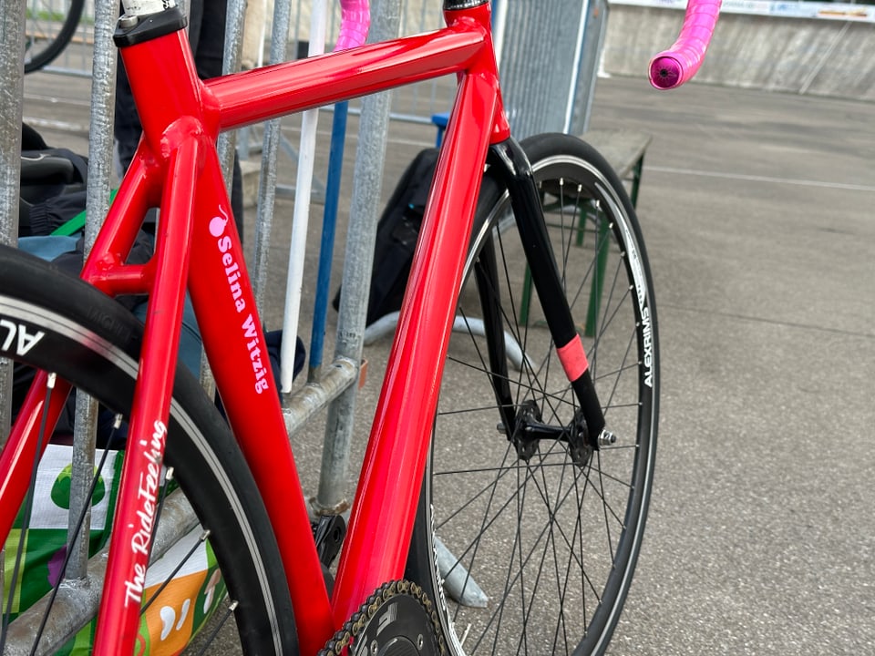 Ein rotes Fahrrad mit pinkem Lenker ist mit pinker Schrift angeschrieben.