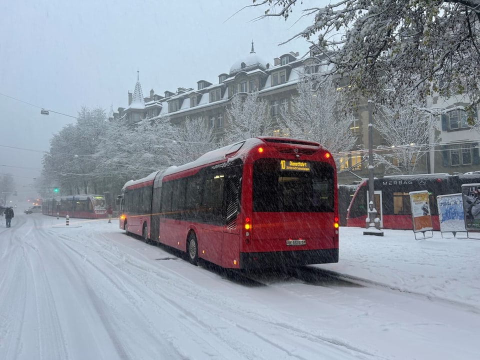 Roter Gelenkbus im Schneesturm auf Stadtstrasse.