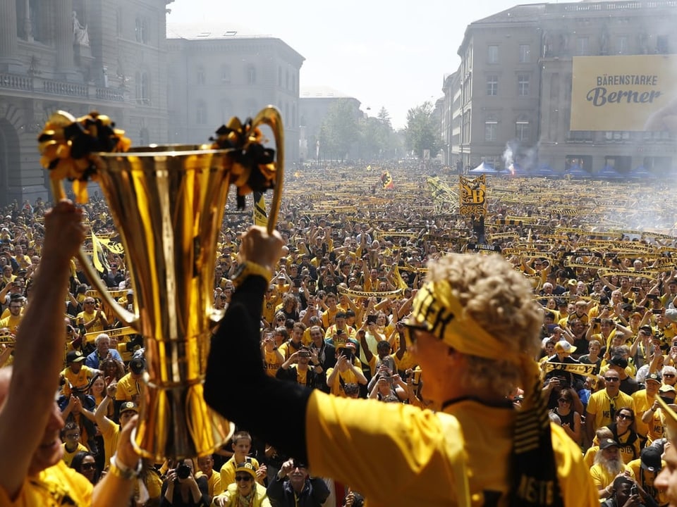 Marco Wölfli hält 2018 den Meister-Pokal in die Höhe. Im Hintergrund ein Platz voller Fans.