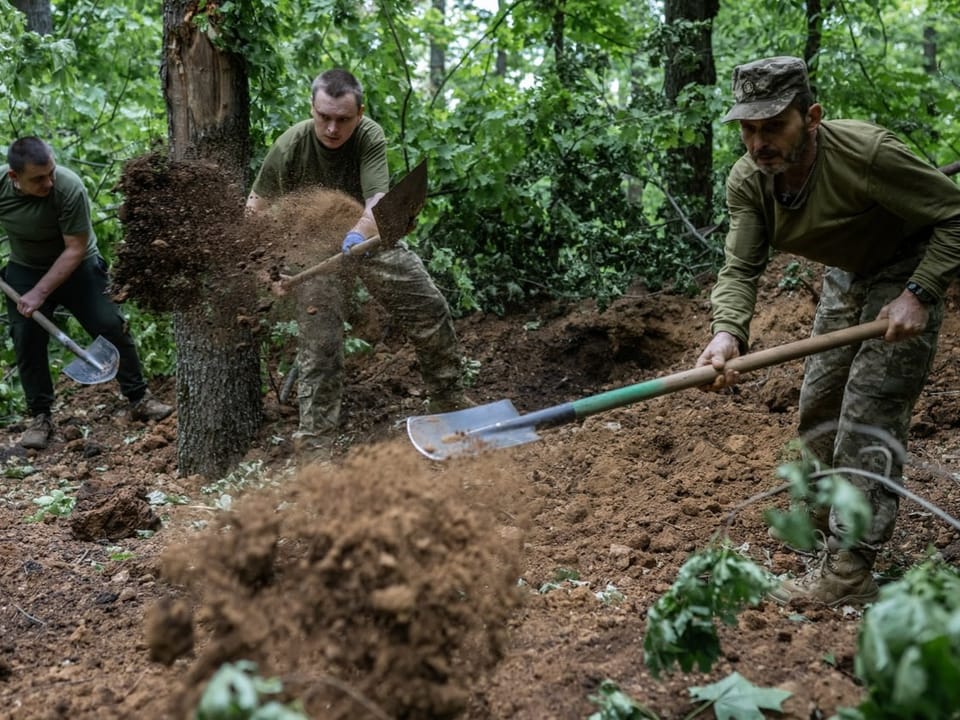 Ukrainische Soldaten bauen einen Graben.