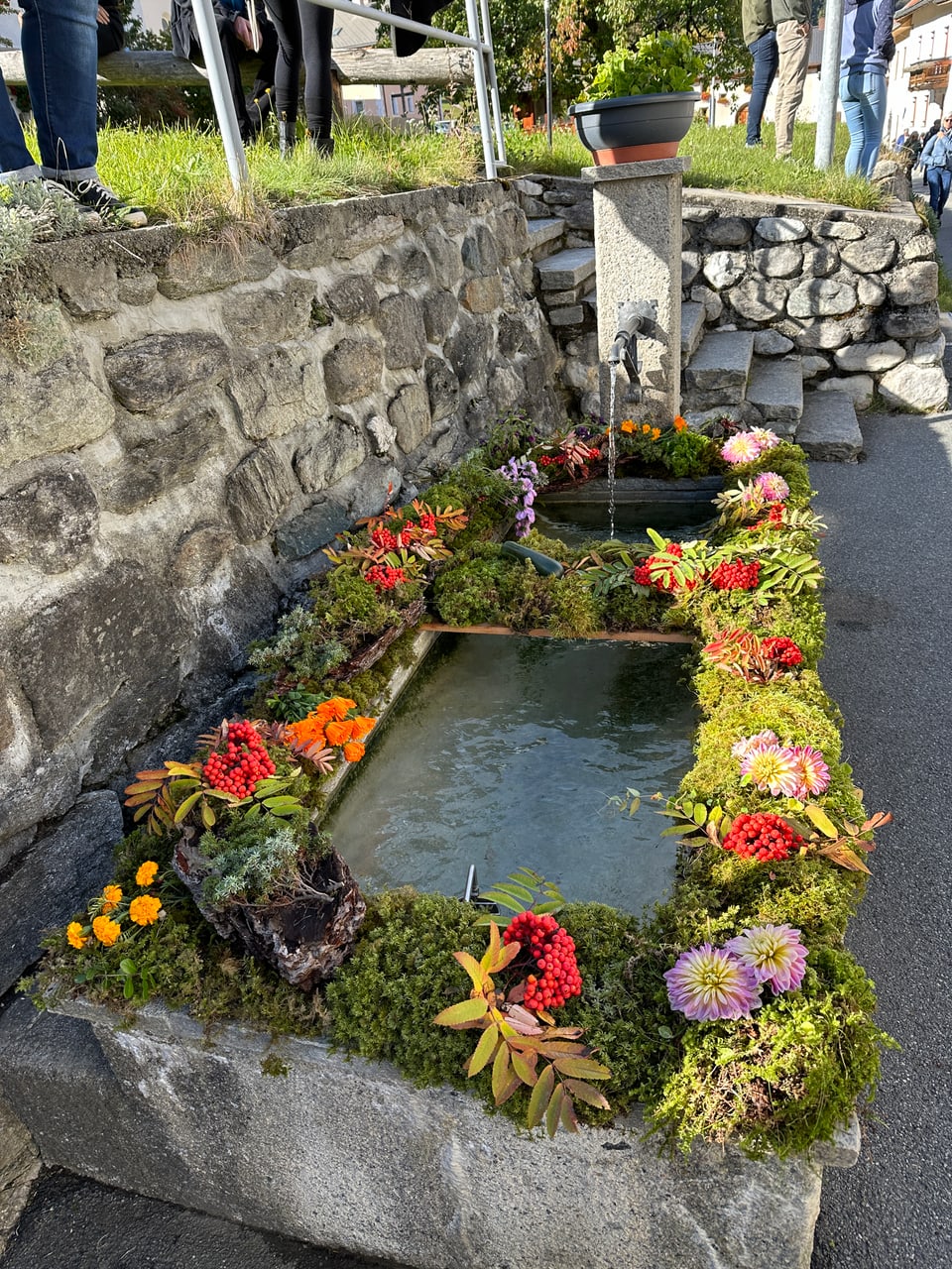 Steinbrunnen mit Blumen und Moos dekoriert.