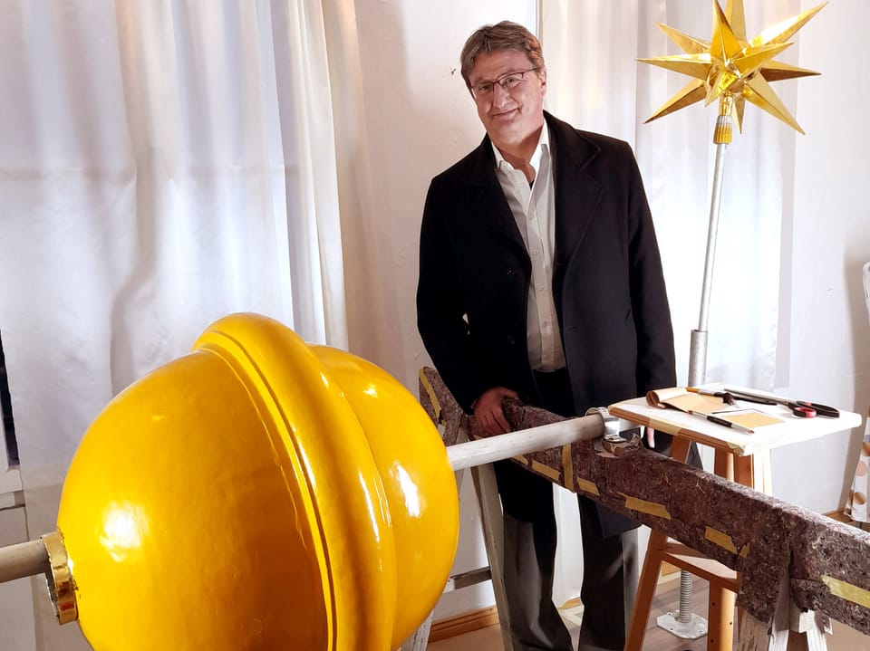 Ein Mann steht neben einer grossen gelben Kugel.