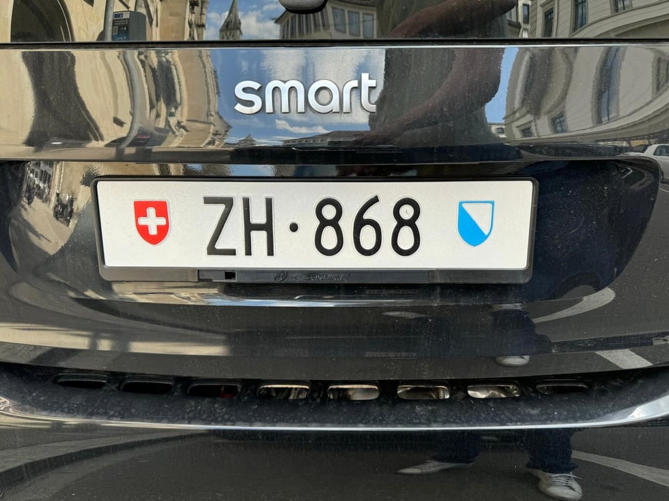 Nahaufnahme eines Nummernschilds eines schwarzen Smart-Autos mit ZH 868.