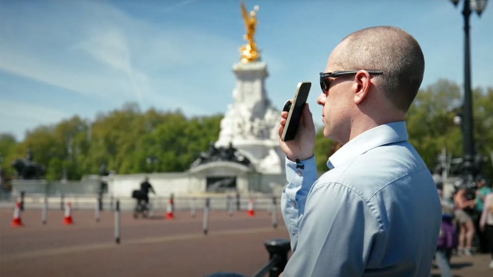 Mann mit Brille hält Smartphone vor Augen