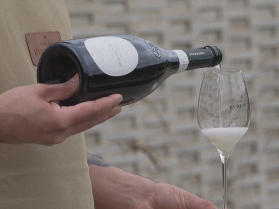 Person schenkt Sekt in ein Glas mit Schaum.