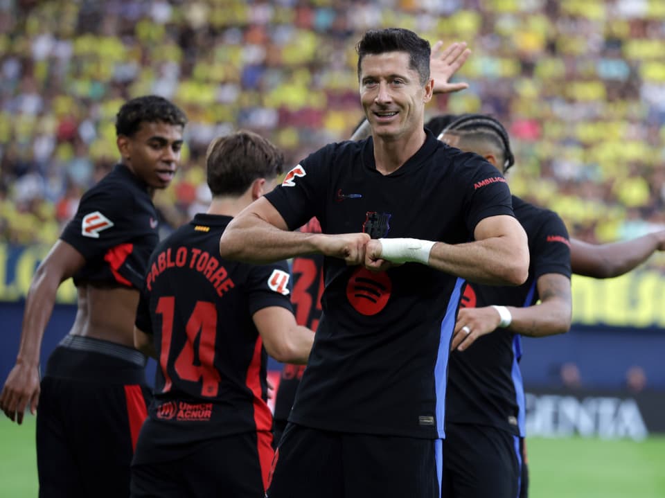 Fussballspieler feiert Tor mit Teamkameraden im Stadion.