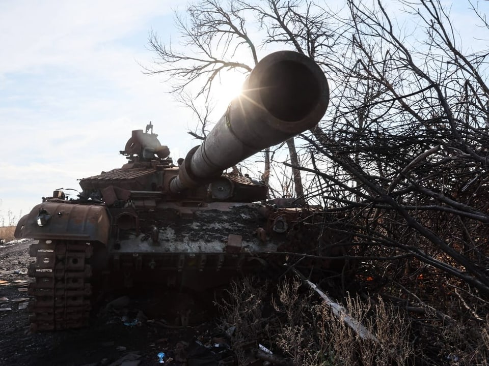 Verlassener Panzer in einer Landschaft mit kargen Bäumen.