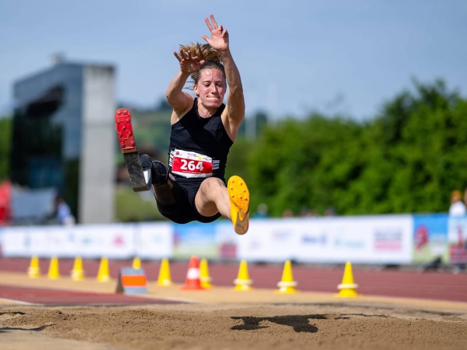 Weitspringerin in der Luft auf einer Outdoor-Leichtathletikanlage.