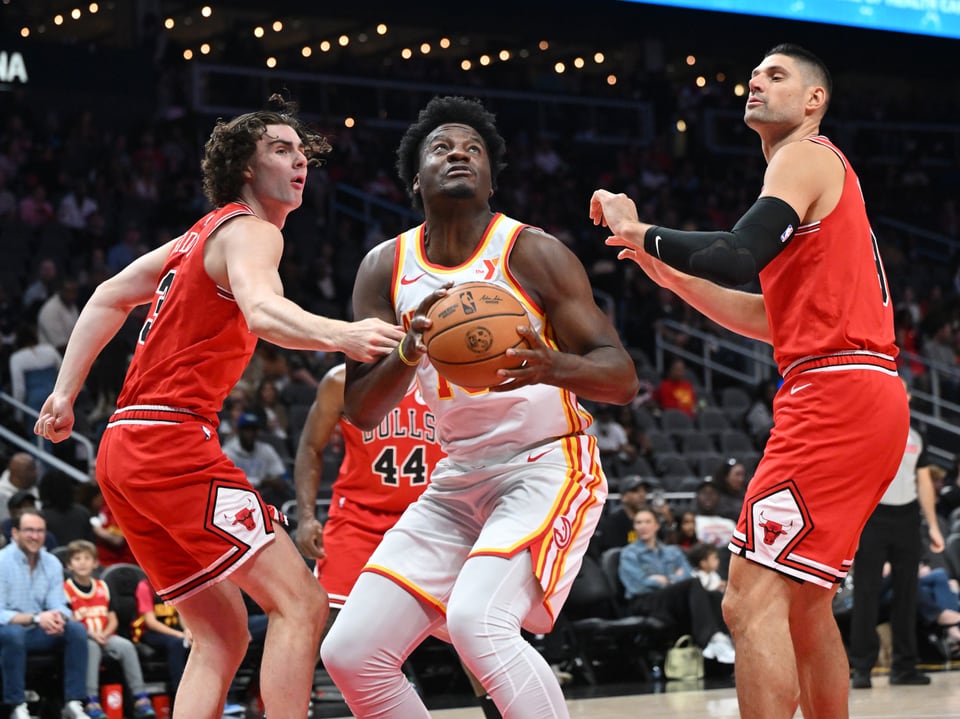 Basketballspieler im Spiel, einer im weissen Trikot mit Ball in der Hand.