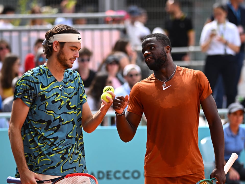 Zwei Tennisspieler schlagen sich nach dem Spiel ab.