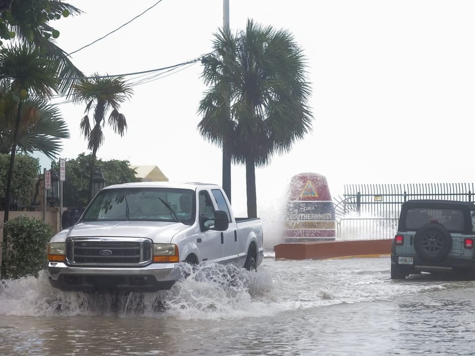 Autofahrer trotzen einer überfluteten Straße in der Nähe der Boje „Southernmost Point“ in Key West, Florida. 