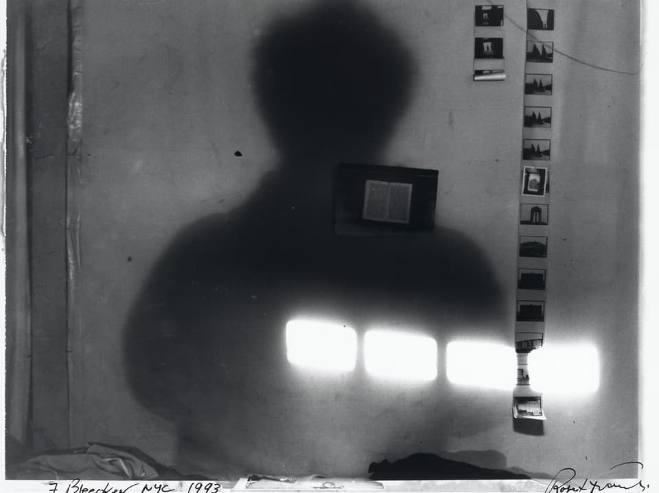 Schatten einer Person an einer Wand mit aufgehängten Fotos.