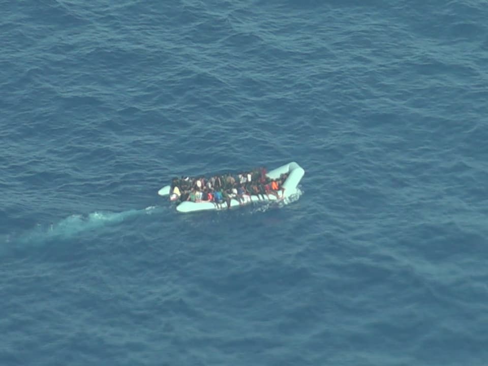 Schlauchboot mit Menschen auf offenem Meer.