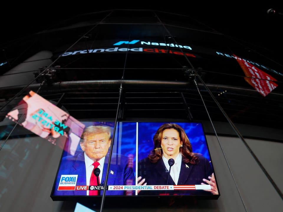 Fernsehbildschirm zeigt Präsidentschaftsdebatte 2024 vor Nasdaq-Gebäude.