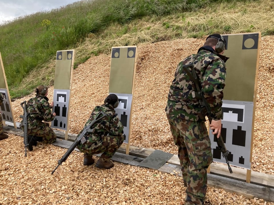 Soldaten in Tarnkleidung bei Schiessübungen auf Zielscheiben.