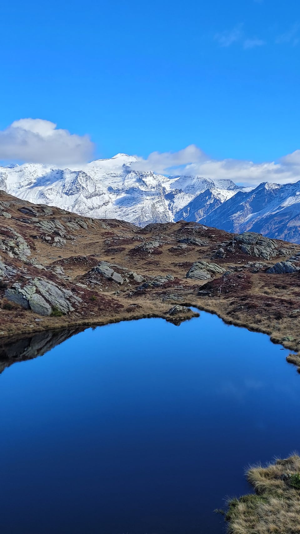 Bergsee mit schneebedeckten Bergen im Hintergrund.