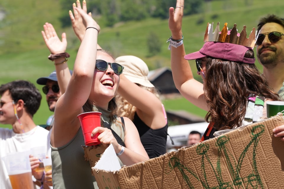 Menschen, die im Freien bei Sonnenschein feiern und lachen am Open Air Lumnezia 2024.