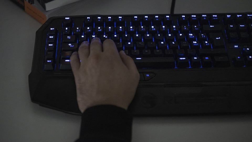 Hand tippt auf beleuchtete Tastatur.