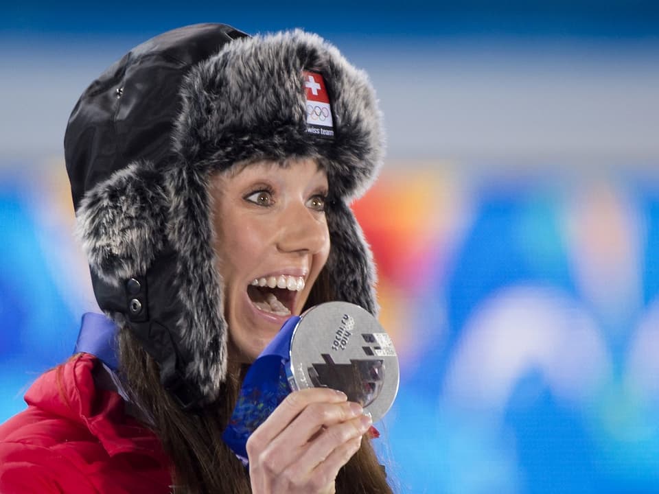 Eine Frau zeigt ihre Silbermedaille.