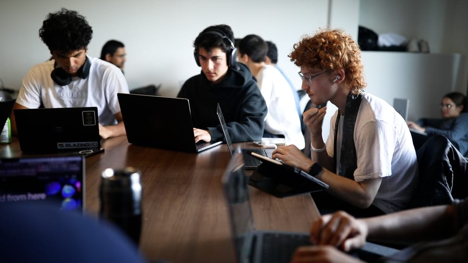 Junge Menschen sitzen vor ihren Laptops.