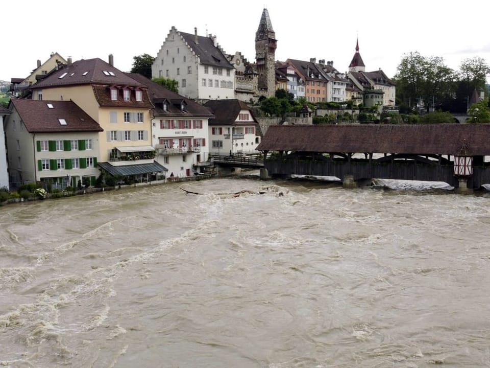 Die überflutete Altstadt von Bad Münster am Fluss Reuss mit einer überdachten Holzbrücke.