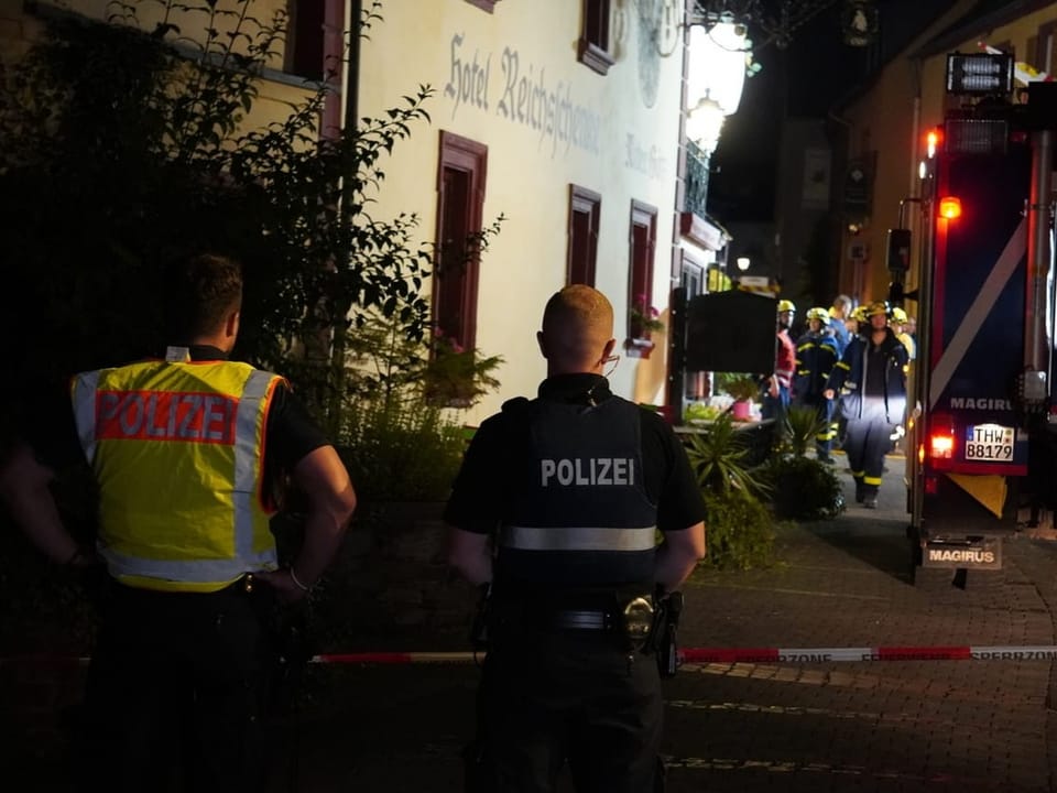 Polizisten und Feuerwehrleute bei nächtlichem Einsatz vor einem Gebäude.