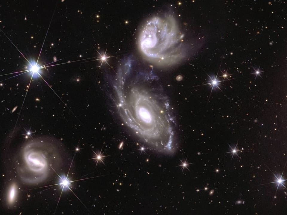 Mehrere Spiralgalaxien im Weltraum mit Sternen.