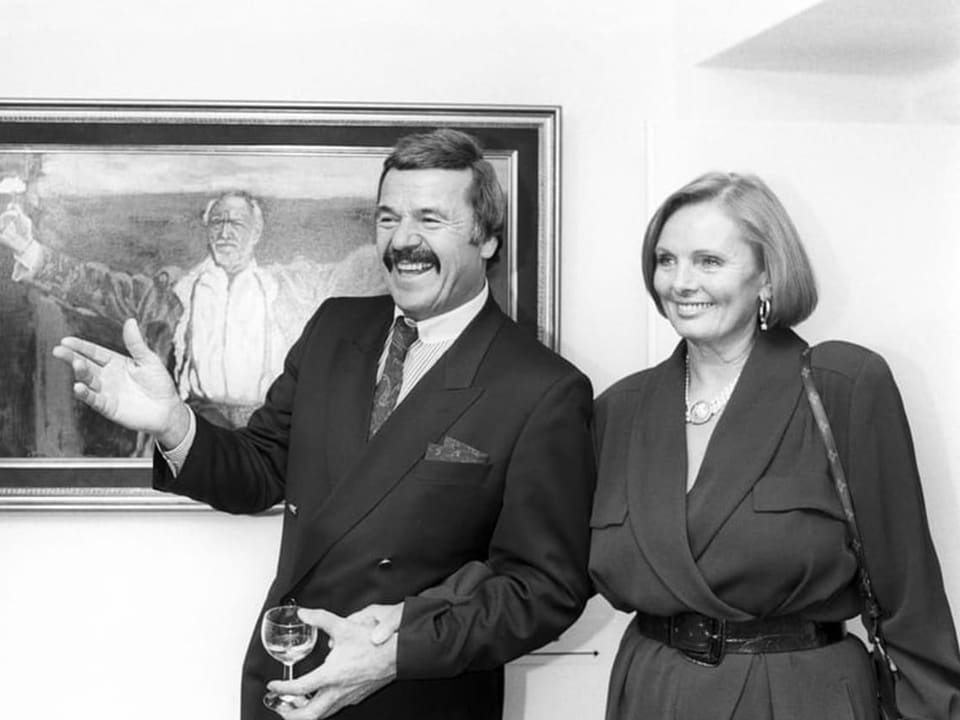Zwei lächelnde Menschen bei einer Kunstgalerie, Mann mit Weinglas.